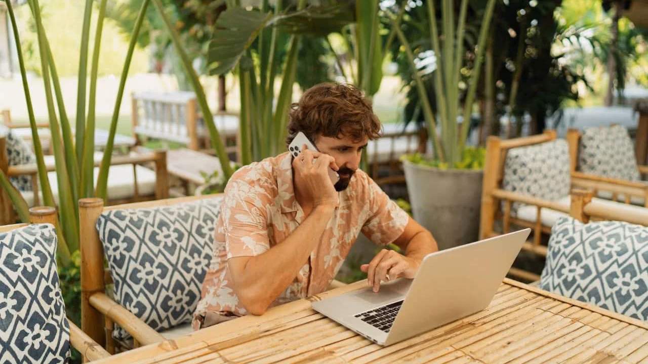 Digital nomad working from a laptop in a Bali cafe with tropical greenery and a remote work setup
