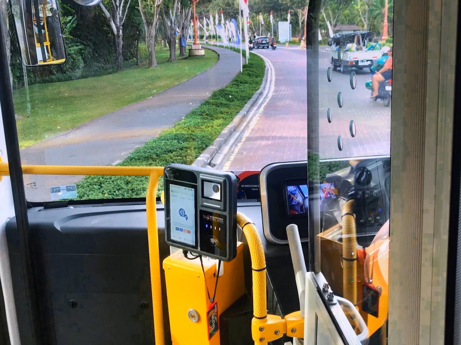 Onboard cashless payment terminal mounted beside the driver on a yellow handrail